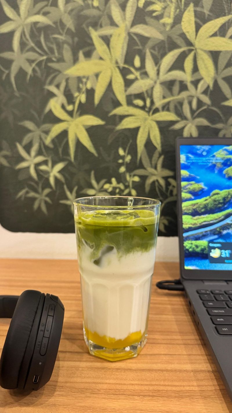 An iced matcha beside a laptop at The Calm Cup