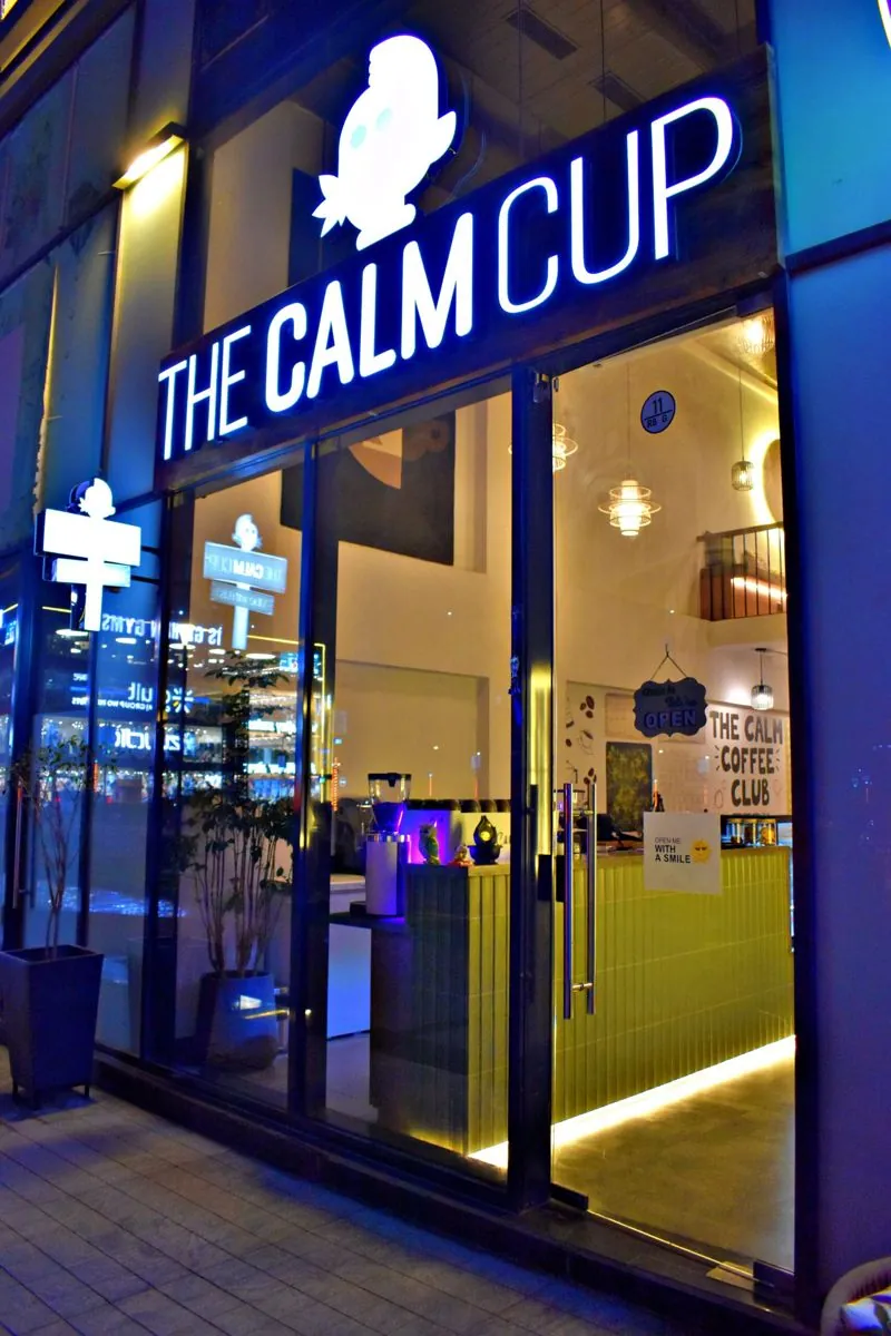 The Calm Cup storefront lit up at night