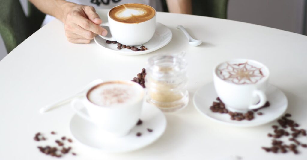 A stylish arrangement of various coffee cups on a café table with a person reaching for one.